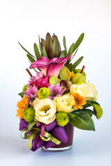 Flower arrangement in a purple vase on white background.