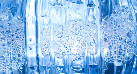 Transparent drops of pure water on a blue smooth surface.