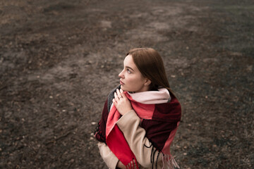 girl wrapped in a red scarf from the cold, looks into the distance