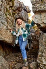 beautiful caucasian blonde female is travelling alone on mountains, attractive woman is casual outdoors clothing among big rocks, hiking