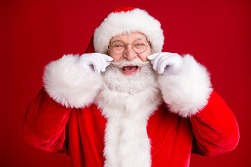 Close up photo of positive crazy santa claus touch his white mustache x-mas fairy atmosphere wear red costume isolated bright shine color background