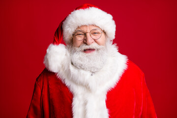 Close up photo of positive cheerful santa claus look in camera wear red costume hat isolated over shine vivid color background