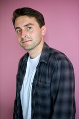 handsome caucasian guy in casual shirt posing isolated on pink background, young male confidently looks at camera
