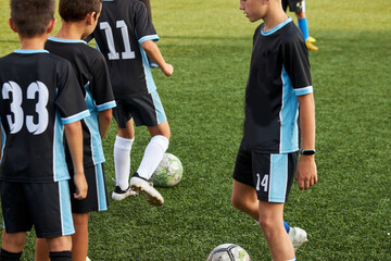 teen boys training soccer or football game in stadium, sportive children kick ball, practice penalty and other tricks