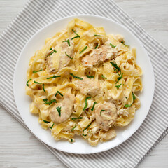 Homemade Chicken Fettuccine Alfredo on a white plate on a white wooden background, top view. Flat lay, overhead, from above.
