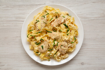 Homemade Chicken Fettuccine Alfredo on a white plate on a white wooden background, top view. Flat lay, overhead, from above.