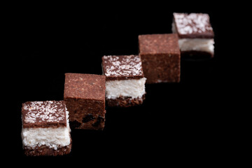 five cookie in chocolate isolated on black plate as a diagonal, three cookies brown and white, two brown cookies.