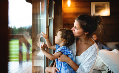 Small girl with parents in wooden cabin, holiday in nature concept.