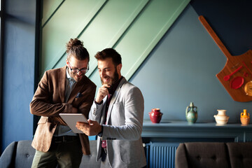 Portrait of happy businessmen using digital devices at meeting