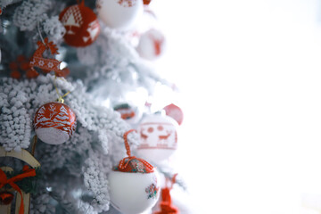 Christmas holiday background. Silver and color bauble hanging from a decorated on tree with bokeh and snow, copy space.