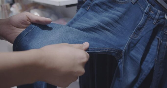 Female Hands choosing to buy Jeans in shopping mall.Touch and catch with jeans.
