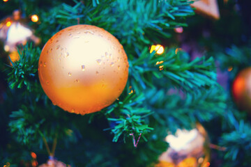 Gold ball on the green Christmas tree and background of garland lights