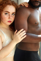 portrait of sensual multi-ethnic couple at home, half-naked black african guy and caucasian redhead female in underwear in love, diverse people