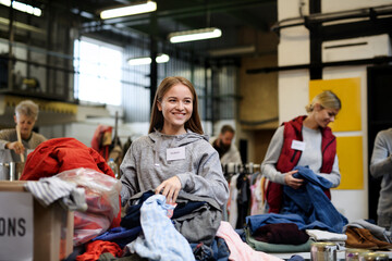 Volunteers sorting out donated clothes in community charity donation center, coronavirus concept. - Powered by Adobe