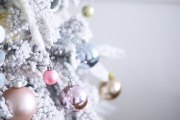 Christmas holiday background. Silver and color bauble hanging from a decorated on tree with bokeh and snow, copy space.