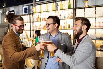 Young businessmen are drinking beer, talking and smiling while resting at the pub
