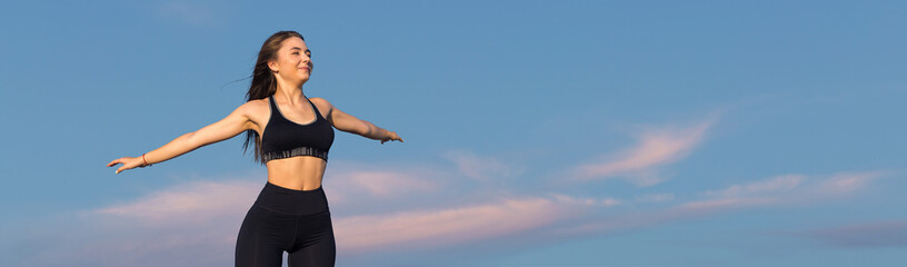 Female posing in sportswear on sky background. The middle part of the body.