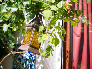 Antic lantern, green plant around, red curtain, outdoor terrace, Mediterranean patio, hanging light