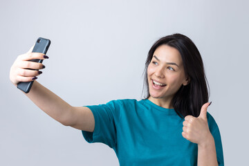 Portrait of a pretty girl taking a selfie isolated over grey background