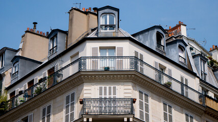 Fototapeta na wymiar Typical front building in Paris, Blue sky and white clouds, roof and attic room, low-angle shot, haussmann facade, front buildings perspective, historic center, artistic view of the city, symmetry 