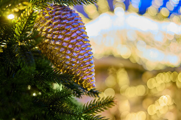 Golden cone on a tree and bokeh in the form of an angel, new year copy space