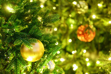 Obraz na płótnie Canvas Christmas tree with yellow ball and green bokeh, copy space. Xmas decorations on new year