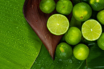Pile of half and whole fresh lime juicy on green banana leaves with clearly water drop on surface