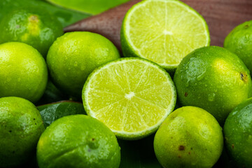 Obraz na płótnie Canvas Close up pile of half and whole fresh lime juicy on green banana leaves with clearly water drop on surface