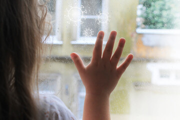 a child looks out the window at isolation due to the coronavirus epidemic