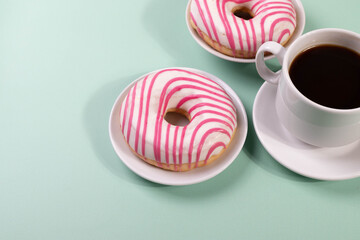 pink doughnuts and a cup of espresso on the mint background