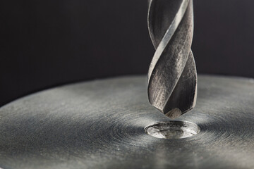 metal drill bit make holes in steel billet on industrial drilling machine. Metal work industry and...