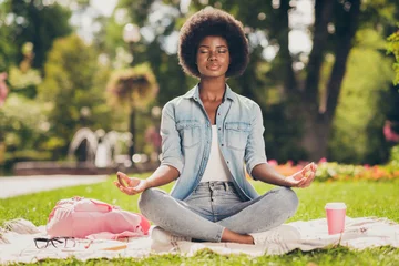 Tuinposter Photo portrait of black skinned young woman sitting in city green park near bag doing yoga asana lotus having pause chill rest closed eyes © deagreez