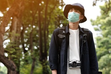 Asian travelers man in the forest with medical face mask to protection the Covid-19  new normal...