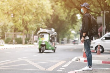 Naklejka premium Asian travelers man in the street with medical face mask to protection the Covid-19, new normal lifestyle