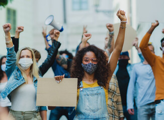 Group of people activists protesting on streets, demonstration and coronavirus concept.