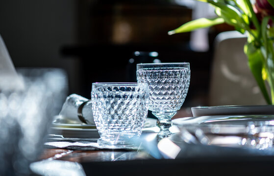 Dinner table is set and ready, portrait photography with focus to glasses with reflecting light on a dinner table, background the china and cutlery is blurred, focus on the Chrystal glass 