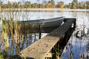 drewniany pomost i biała łódka nad jeziorem