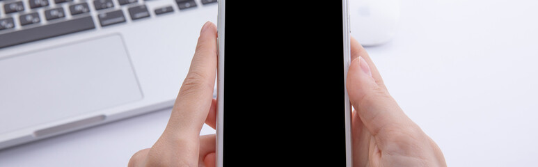 top view of female hands top view of female hands using smartphone over desktop with laptop and earphones, work concept using smartphone over desktop with laptop and earphones, work concept . High