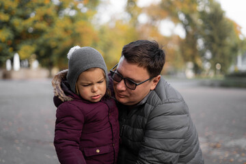 Fototapeta premium Father comforting toddler child, parent support. Autumn, yellow leaves. Outdoors kids activity