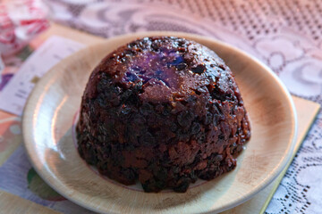 Christmas pudding dessert  lit with a burning brandy flame served at dinner time on Christmas day during the festive season in December stock photo image