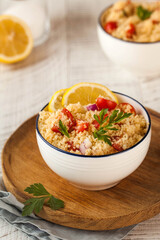 Tabouleh is an Arabic vegetarian salad made with couscous, tomatoes, parsley. Healthy lunch on a wooden background.