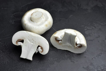 Champignon mushrooms on black slate background.