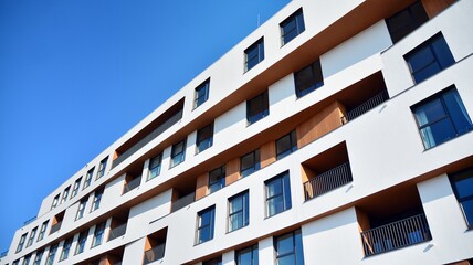 Obraz premium Modern and new apartment building. Multistoried modern, new and stylish living block of flats. Facades on a bright sunny day with sunbeams in the blue sky.