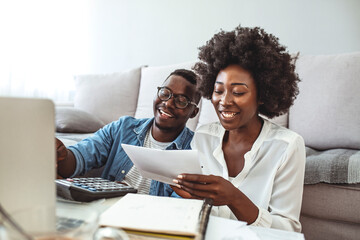 Photo of cheerful loving young couple using laptop and analyzing their finances with documents....