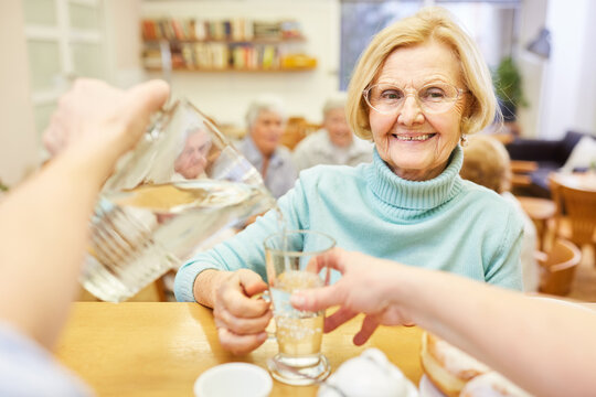 Geriatric nurse pours water from a carafe