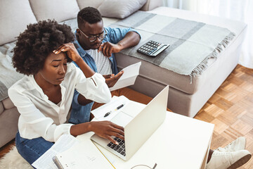 Desperate couple doing their accounts in the living room. Serious African American couple...
