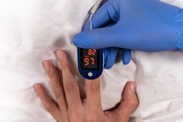 A gloved doctor measures oxygen in the blood of a patient with suspected coronavirus. The oximeter...