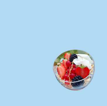 Coconut muesli glass bowl with fresh fruits, strawberries, currants, blueberries over pastel background