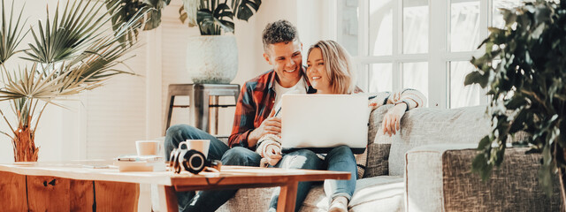 Couple in love. Young family watching TV series using laptop in cozy loft apartment