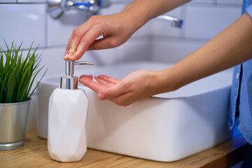 Person washes hands in the bathroom sink with liquid antibacterial soap. Daily protection and...